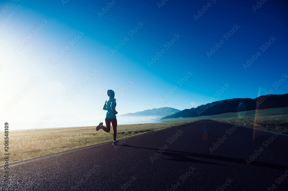 Young fitness sporty woman running on country road