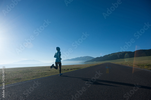 Young fitness sporty woman running on country road © lzf