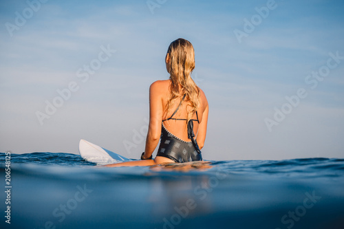 Surf woman sit on the surfboard. Woman with surfboard in ocean. Surfer and ocean