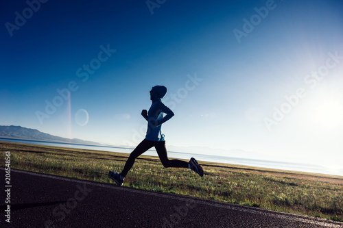 Young fitness sporty woman running on country road