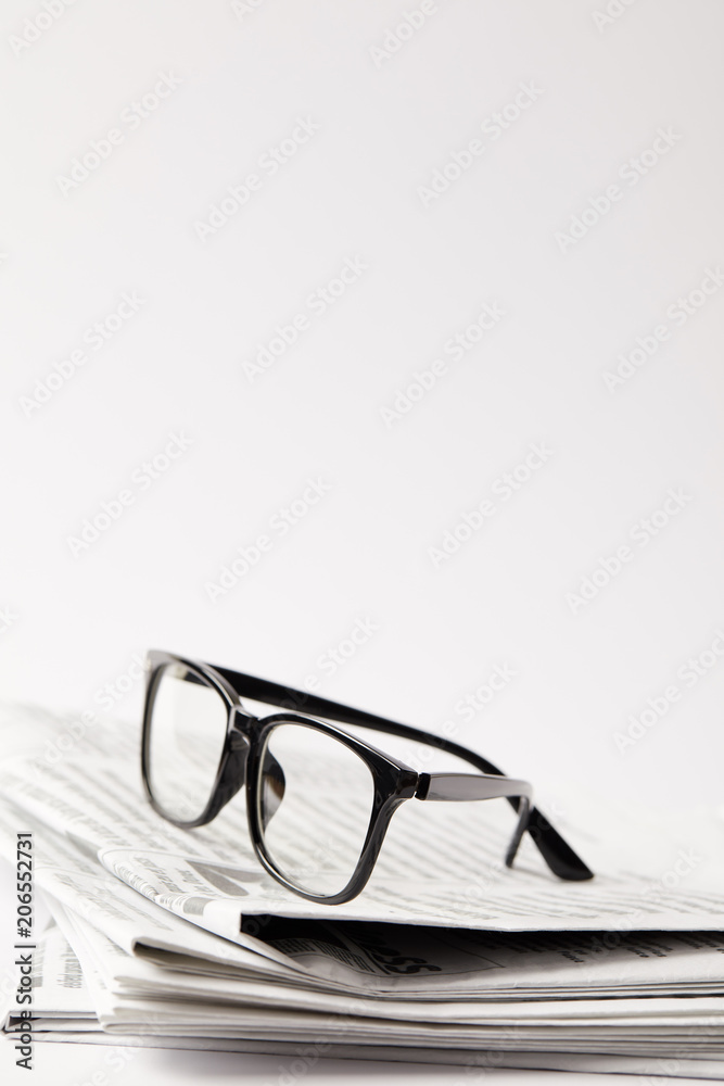 close up of newspapers with black eyeglasses, on white with copy space close up of newspapers with black eyeglasses, on white with copy space