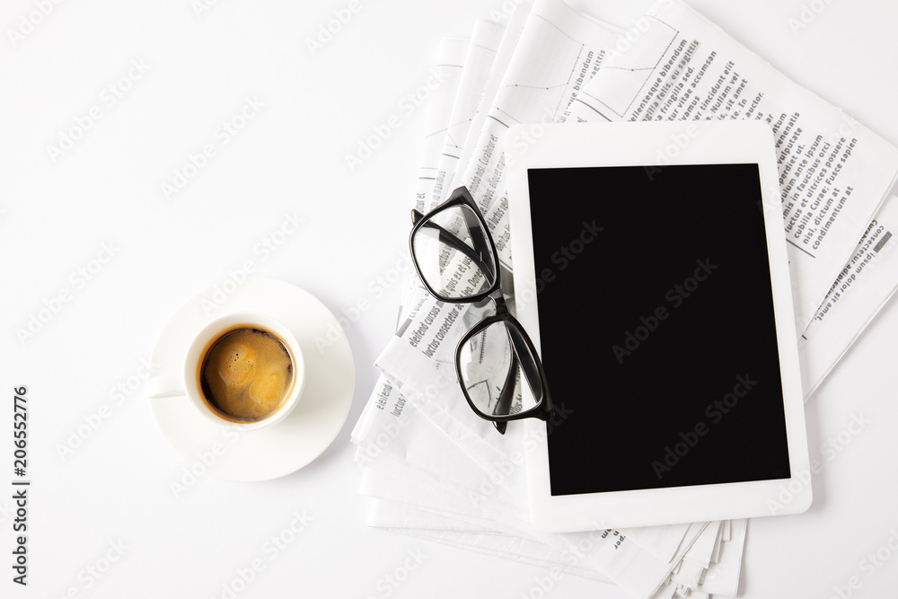 top view of glasses, cup of coffee, digital tablet and pile of newspapers, on white
