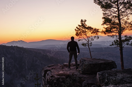 A man stands on the edge of a rock