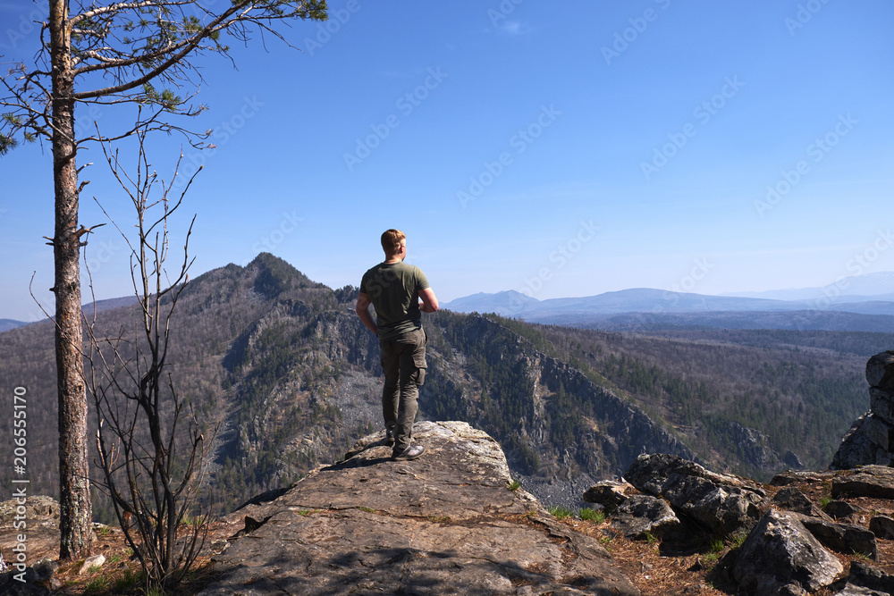 A man stands on the edge of a rock