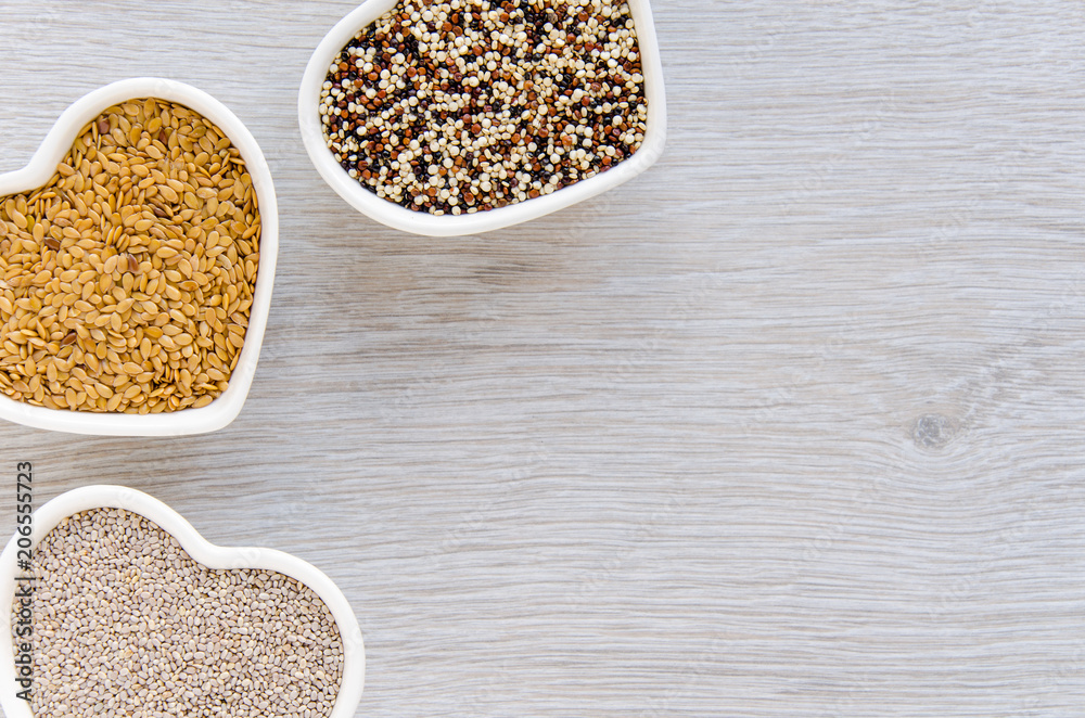 Flax, chia and quinoa seeds in heart shaped bowls with copy space Flax, chia and quinoa seeds in heart shaped bowls with copy space