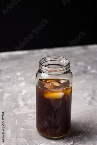 iced coffee drink in a glass botle concrete background copy space