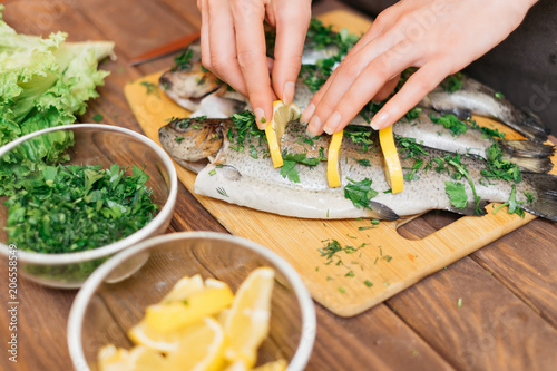 Photography Woman preparing fish with lemons and greenery.