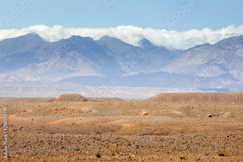stone desert with mountains peaks and clouds in Morocco