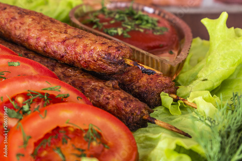 lulia kebab on a salad with tomatoes and dill