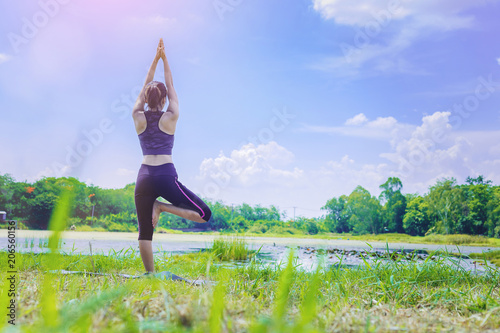 Young woman doing yoga pose beside the lake.