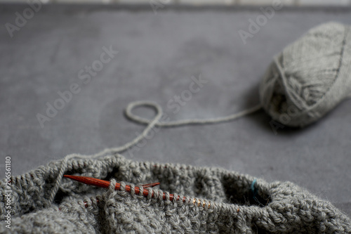 Gray unfinished sweater with a ball of threads on a gray background