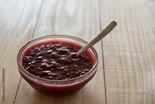 Homemade strawberry jam in a a glass bowl with fresh ripe strawberries on a wooden table