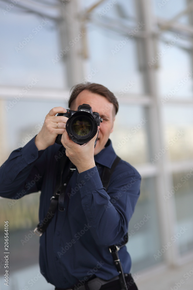 The work of the photographer. A serious man is holding a camera. Journalist. Paparazzi