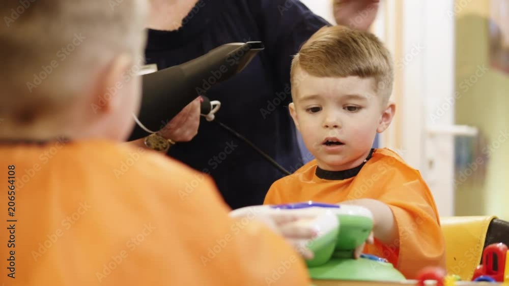 Child hairstyle. Hairdresser working with small boy in Stylist combing hair child