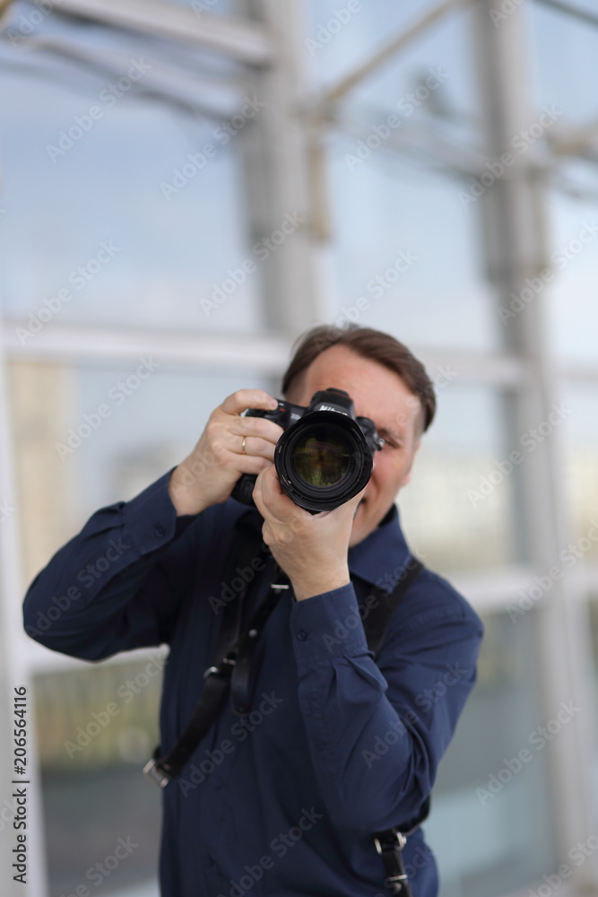 The work of the photographer. A serious man is holding a camera. Journalist. Paparazzi The work of the photographer. A serious man is holding a camera. Journalist. Paparazzi
