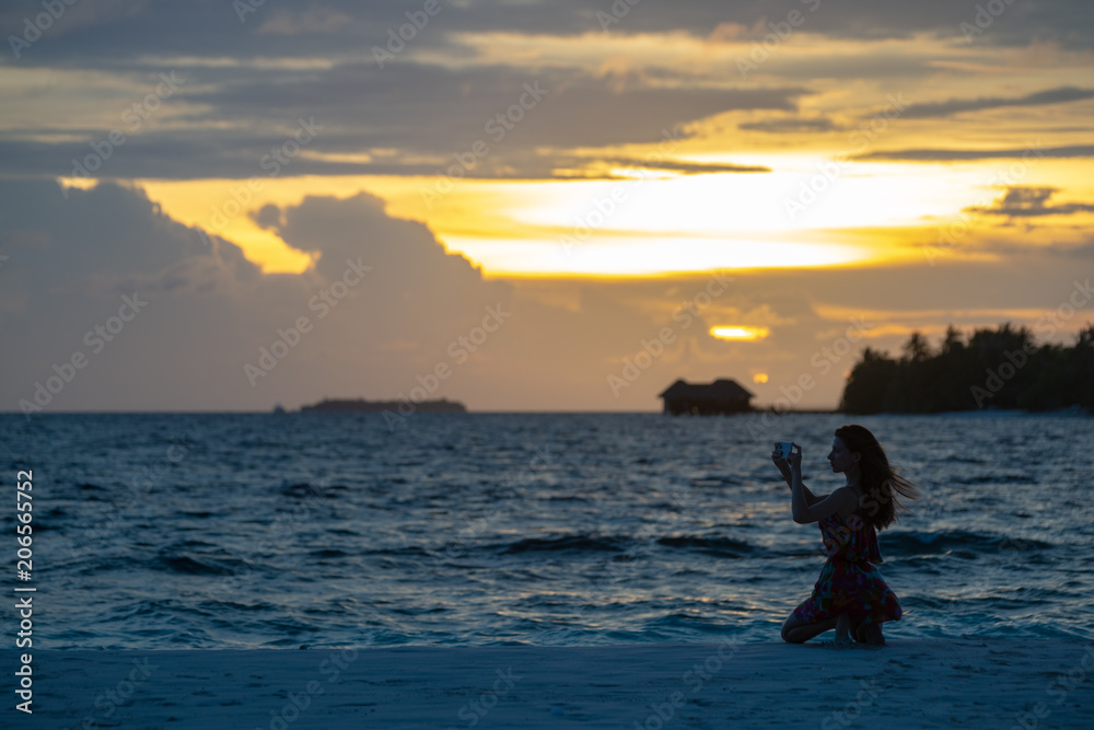 Girl against a beach sunset makes a selfie