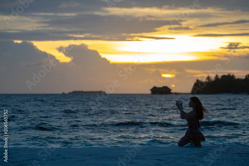Girl against a beach sunset makes a selfie