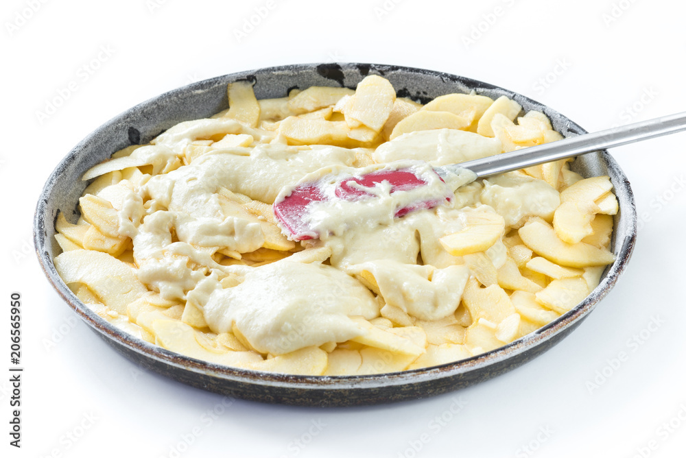 Preparation of an apple pie, spreading the dough on the apples. White background Preparation of an apple pie, spreading the dough on the apples. White background
