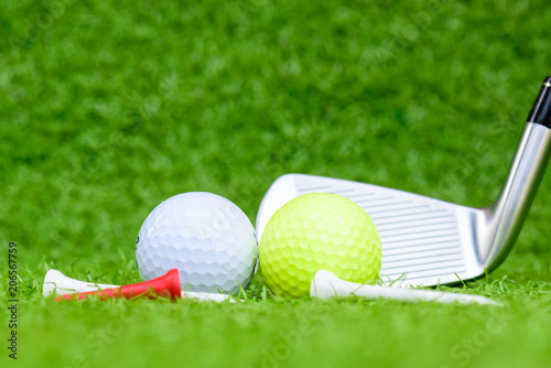 Close up golf ball, golf clubs driver and tee on green grass field background.
