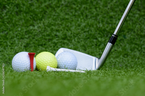 Close up golf ball, golf clubs driver and tee on green grass field background.