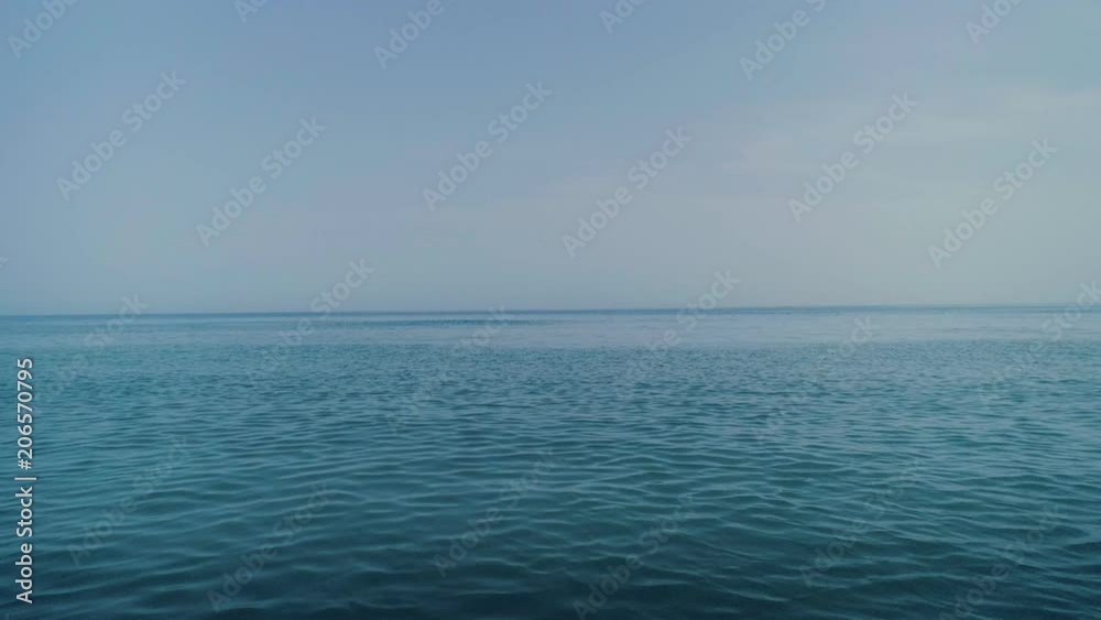 Aerial drone steady panning shot of calm and tranquil blue sea or ocean water surface, swaying waves into horizon, turquoise colors, concept peace and serenity, clean energy and meditation Aerial drone steady panning shot of calm and tranquil blue sea or ocean water surface, swaying waves into horizon, turquoise colors, concept peace and serenity, clean energy and meditation