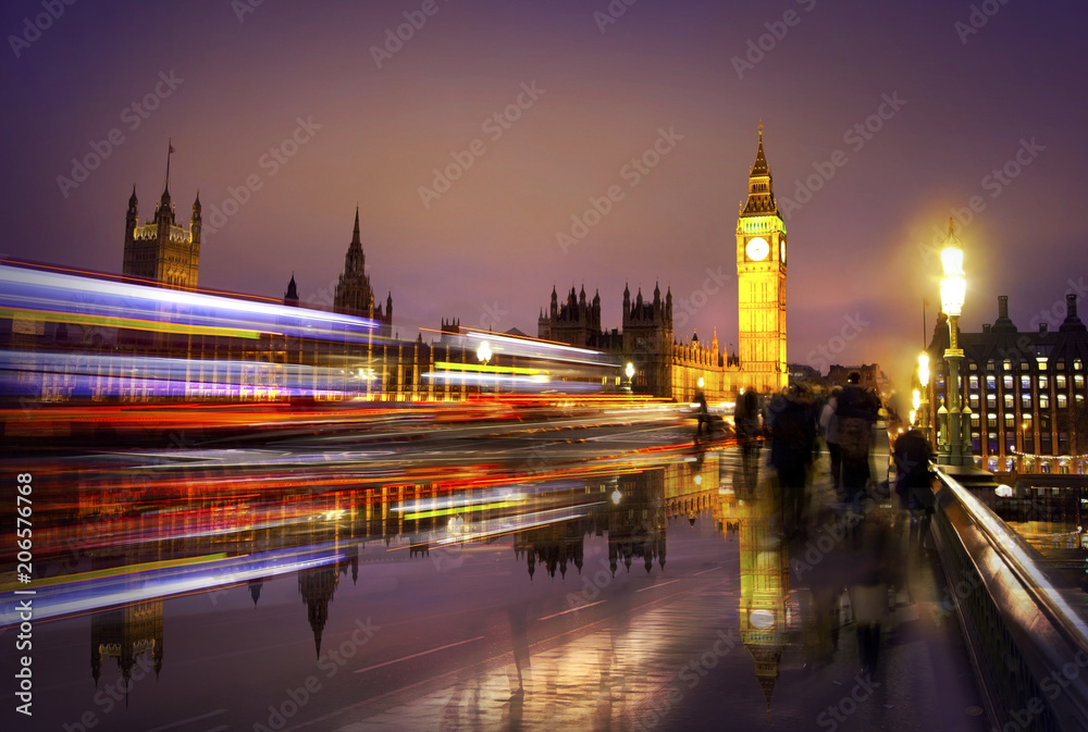 Big Ben, hoses of Parliament at night. View from the Westminster bridge. Traffic lights and walking people blur reflects on the wet road
