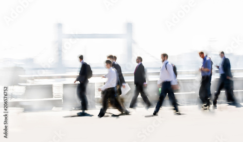 Group of business people walking over London bridge to the City of London. Early morning rush, modern life concept