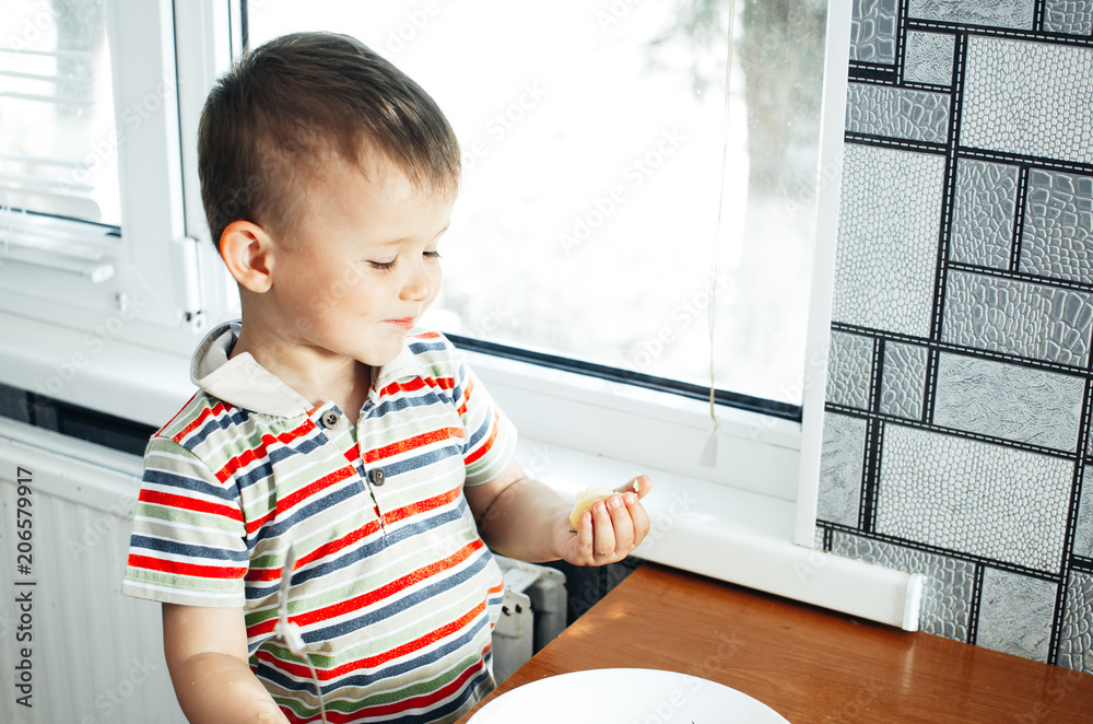 the child in the kitchen with a fork eating young potatoes the child in the kitchen with a fork eating young potatoes