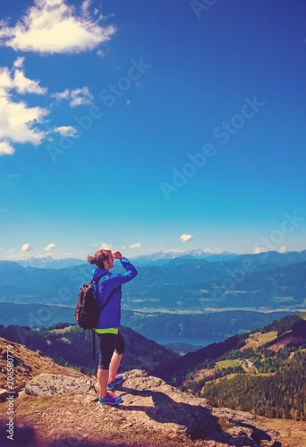 woman standing on the top of a mountain with wonderful view to a lake