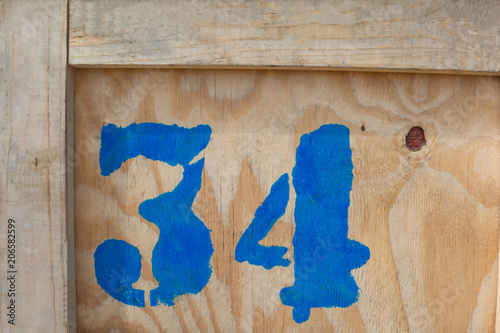 Fotografi The number 34 is written in blue paint on a wooden box