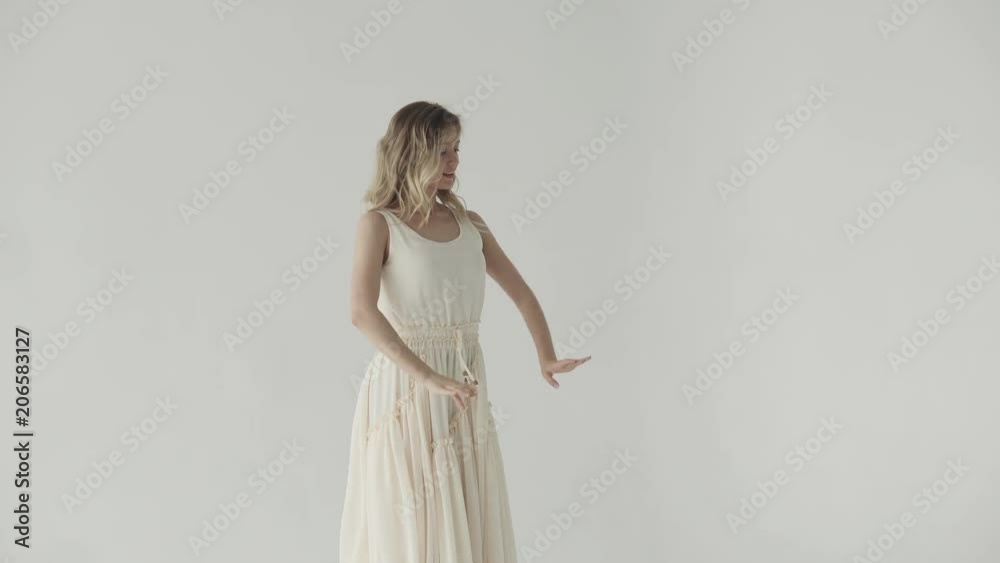 attractive girl is dancing in a white dress on a light background. attractive girl is dancing in a white dress on a light background.