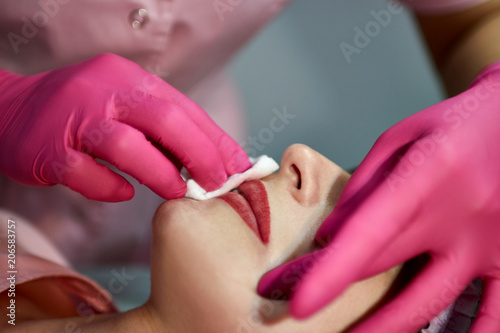 the master in the beauty salon makes a tattoo of the lips of the client