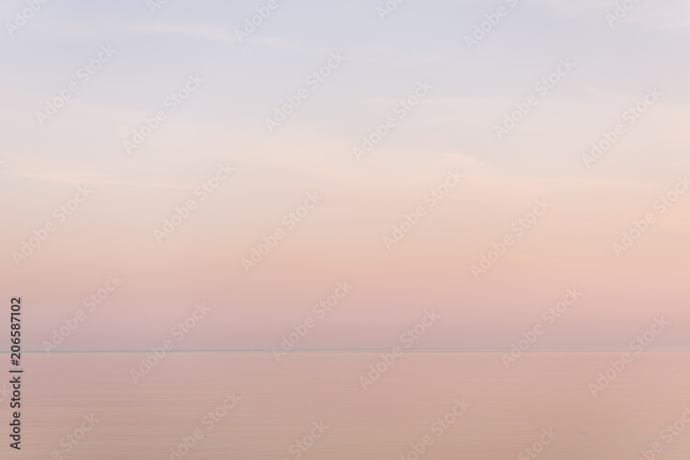 Majestic sunset in pastel tones over calm water surface.