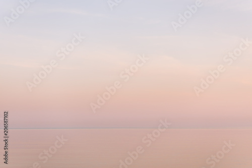 Majestic sunset in pastel tones over calm water surface.