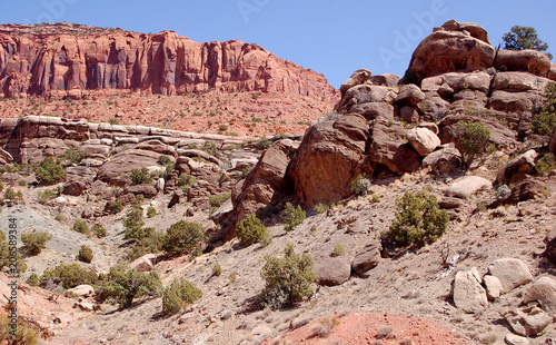 Boulder strewn redrock hillside with red mesa in the Bears Ears wilderness of the Southern Utah desert