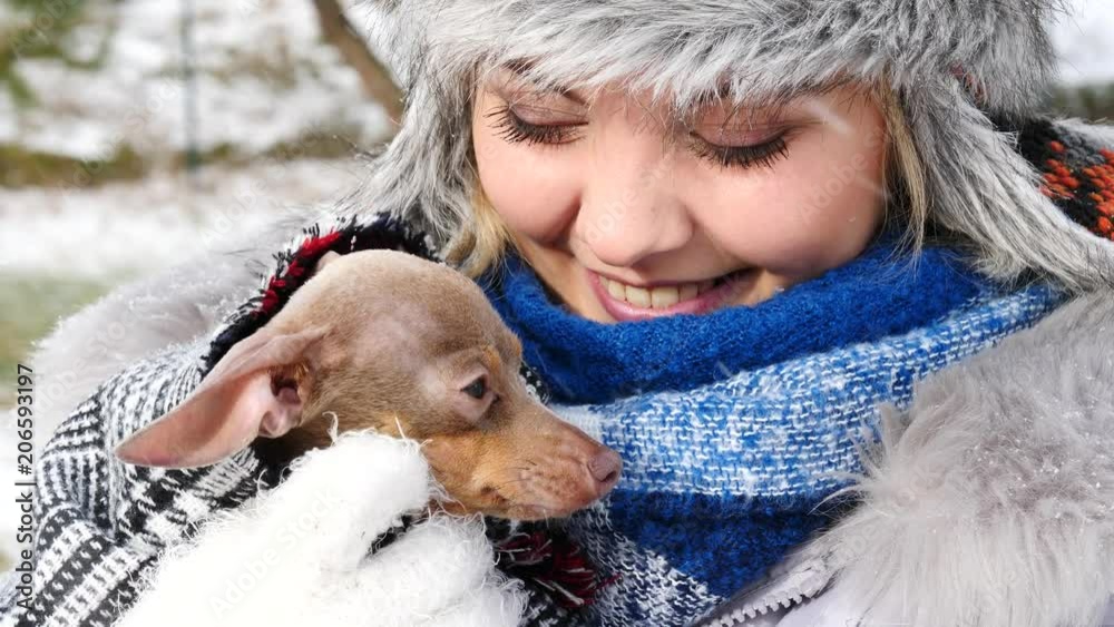 Young woman playing with her dog, pinscher ratter prazsky krysarik, outdoor during winter weather. Female hugging with love her puppy. Young woman playing with her dog, pinscher ratter prazsky krysarik, outdoor during winter weather. Female hugging with love her puppy.