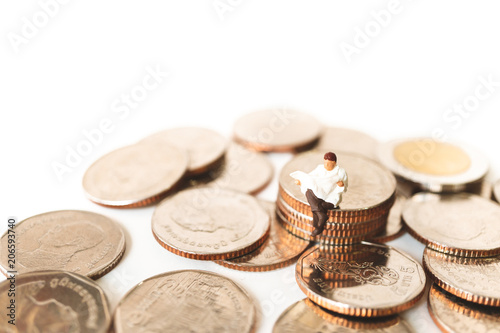 Miniature people  man reading action on stack coins using as business concept