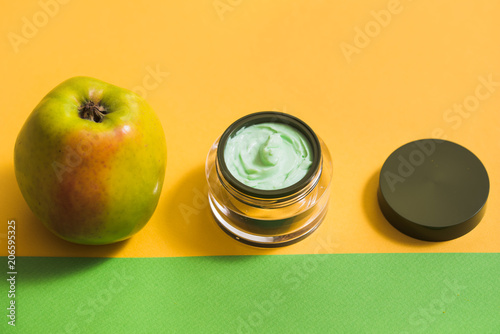 cream for the face, green apple, yellow daisy on a bright background. Natural cosmetics photo