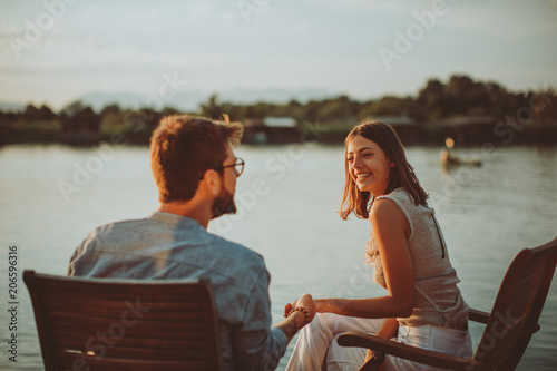 Young couple in love flirting by the river at sunset