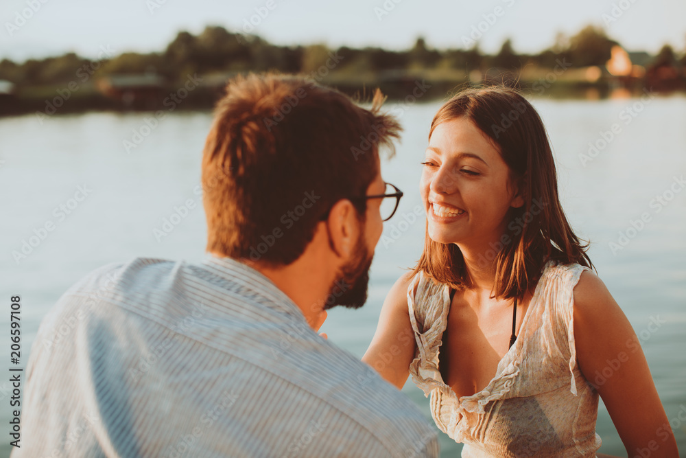 Young couple in love flirting by the river at sunset Young couple in love flirting by the river at sunset