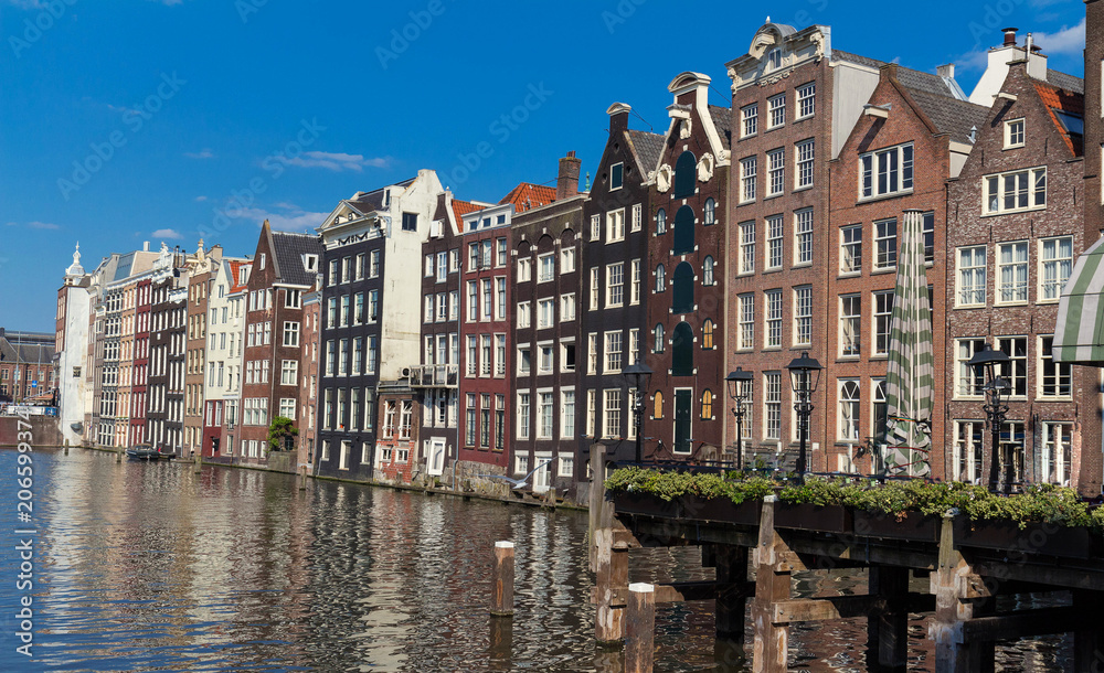 Row of ancient canal houses in the Dutch capital city Amsterdam against a blue sky