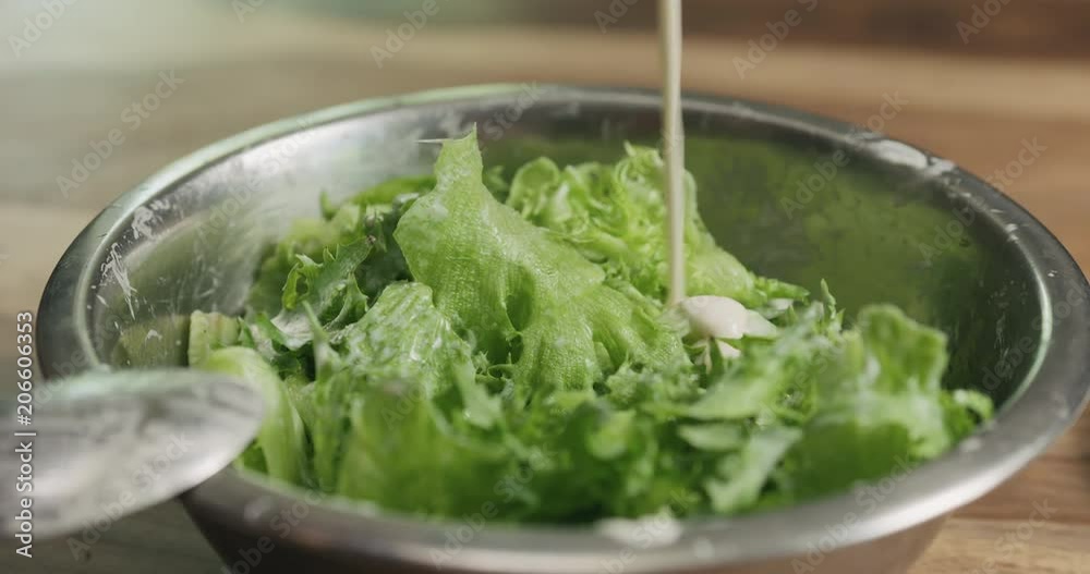 Slow motion closeup mixing frillis salad leaves with caesar sauce Slow motion closeup mixing frillis salad leaves with caesar sauce