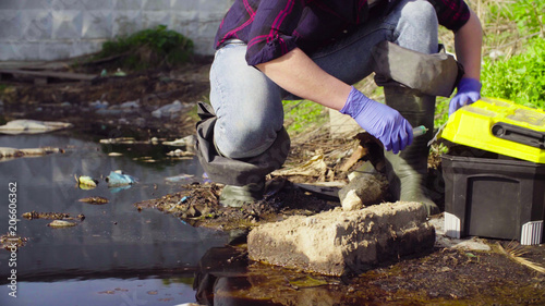 Close up hands of woman scientist ecologist opening toolbox near the big dirty puddle.