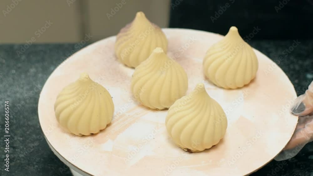Close up of five meringue pastries being painted by confectioner. Concept of: confectionery shop, kitchen table, pastries cake, meringue cookies. Close up of five meringue pastries being painted by confectioner. Concept of: confectionery shop, kitchen table, pastries cake, meringue cookies.