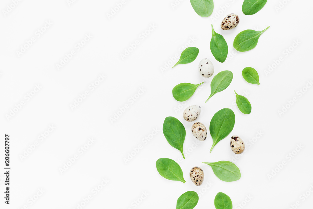 Green spinach leaves and quail eggs for a healthy breakfast on white background top view. Flat lay.