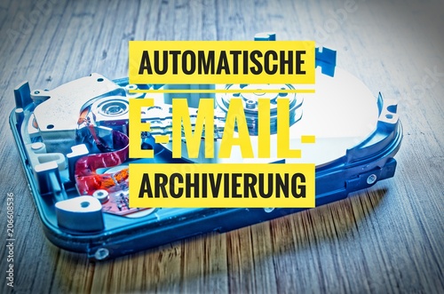 Hard drive 3.5 inches as a data storage with motherboard on a bamboo table and in german Automatische E-Mail-Archivierung in english Automatic e-mail archiving