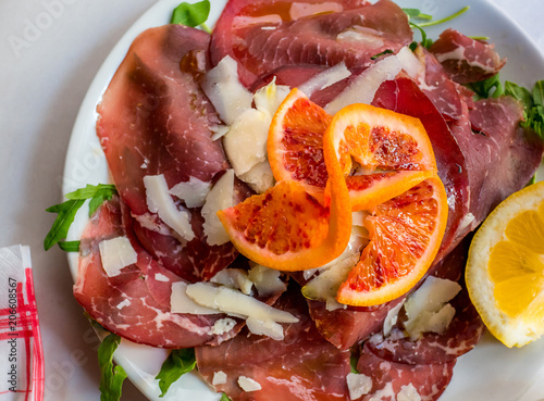 Slices of Bresaola itaian meat with parmesan, orange and lemon. photo