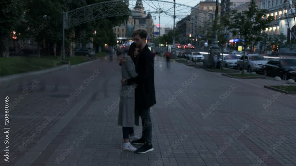 Couple hug and stay without moving on the street in evening time. Smashed crowd of people passing by. Time lapse. Couple hug and stay without moving on the street in evening time. Smashed crowd of people passing by. Time lapse.