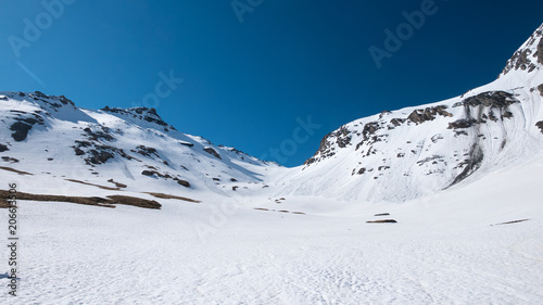 The Alps in springtime, sunny day snowy landscape ski resort, high mountain peaks in the alpine arch, avalanche danger.