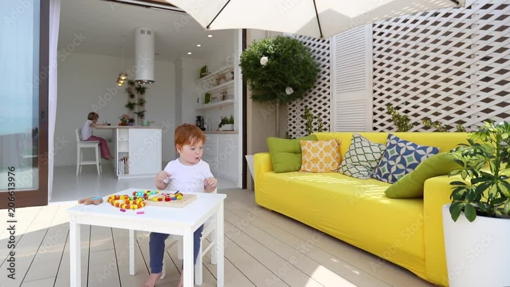 happy toddler baby boy playing games on patio at home at sunny day